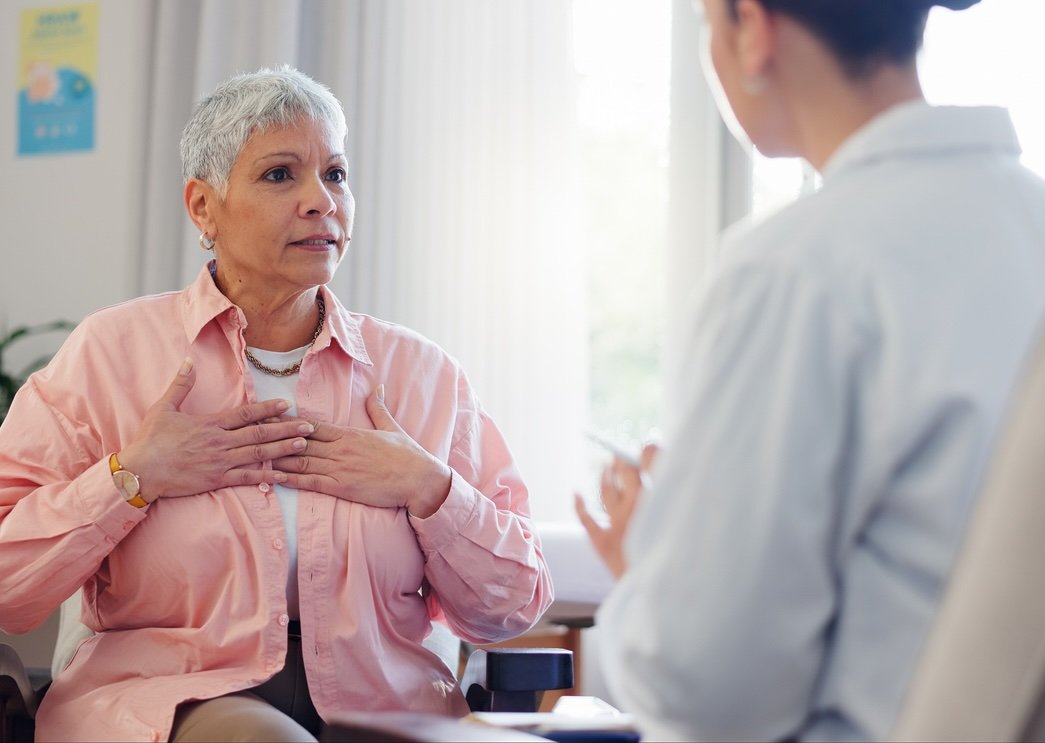 Doctor, consultation and elderly woman with chest pain for heart disease, advice and medical checkup. Healthcare, patient and worker with discussion for cardiac arrhythmia, palpitations and diagnosis