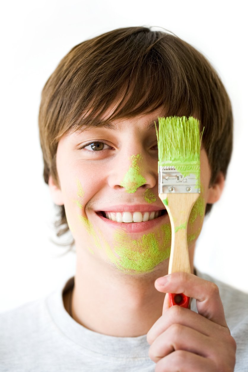Image of joyful guy hiding one of eyes behind paintbrush with green color   Note to inspector: the image is pre-Sept 1 2009